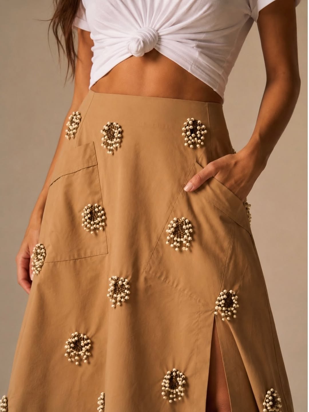 Close-up view focusing on the waist and hip area of the same tan skirt, highlighting the beaded floral details and patchwork seams.