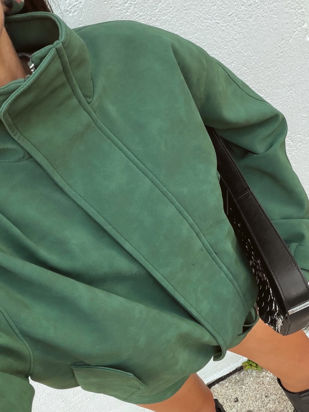 Extreme close-up of the green suede fabric texture on the jacket shoulder.