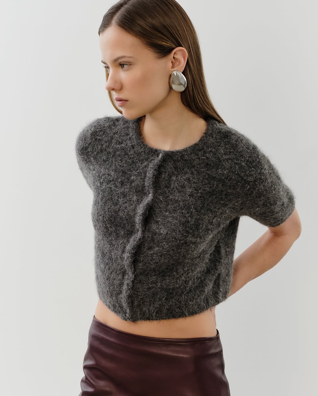 Close-up side view of the same grey textured cardigan and brown skirt combination.