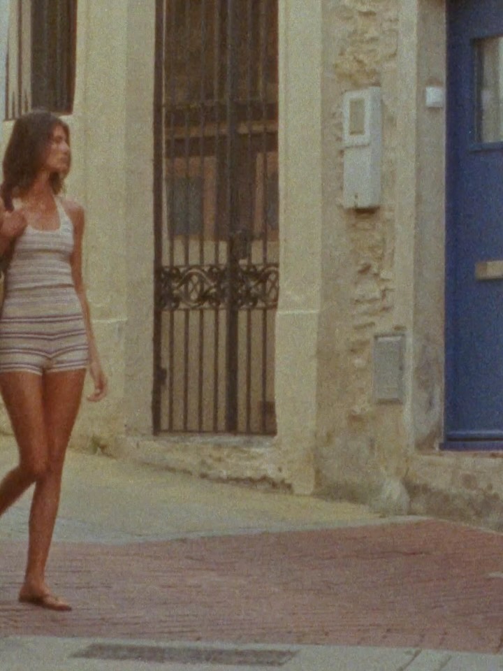 Side profile of a model walking down a street wearing the striped two-piece set.