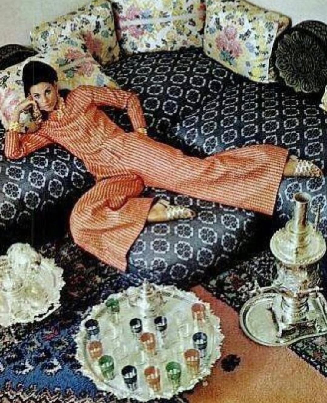Mood image featuring a woman reclining on a sofa wearing a red striped outfit.