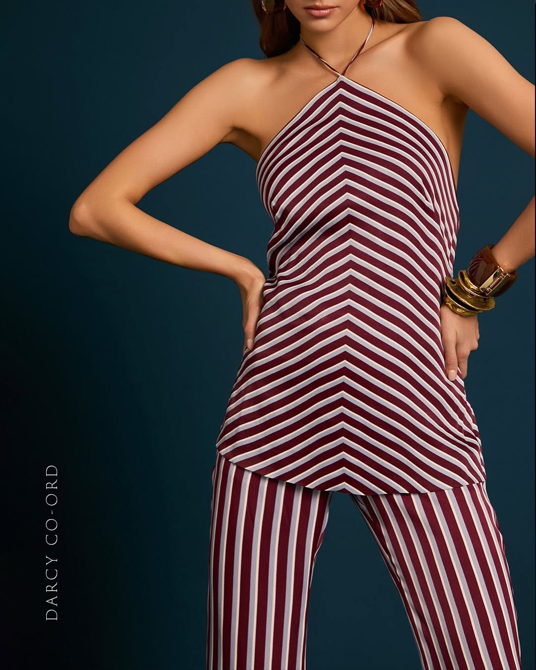 Close-up crop of the torso showing the asymmetrical neckline and chevron stripe pattern of the halter top.