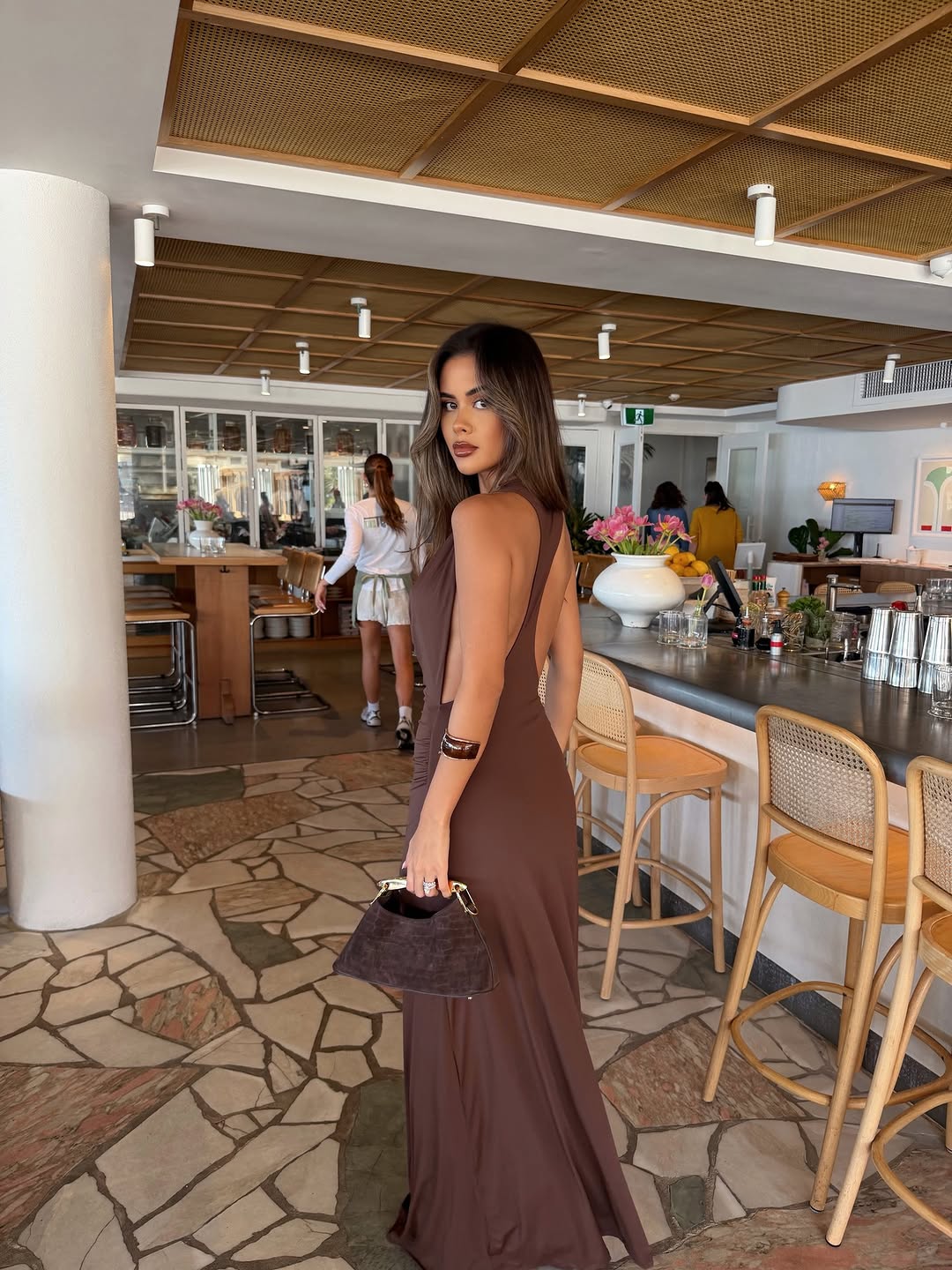 Rear/side angle highlighting the low-back cut of the brown maxi dress.