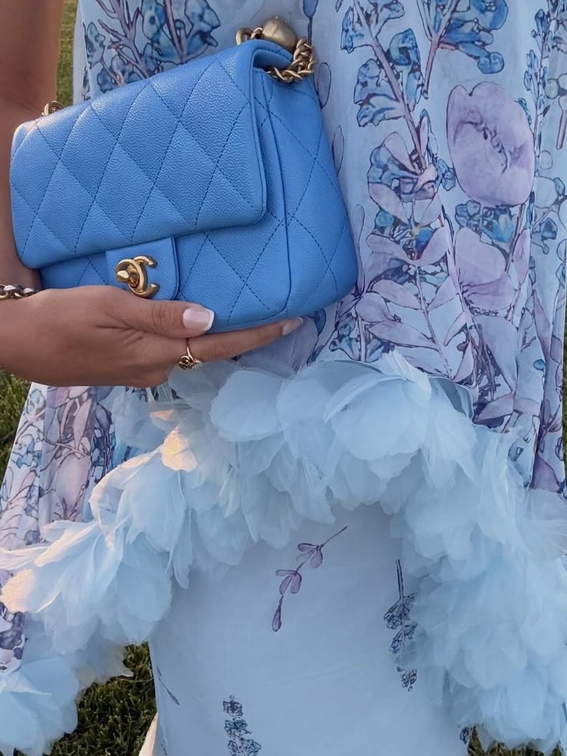 Close-up detail of the dress fabric showing the floral pattern and textured tulle ruffle trim.