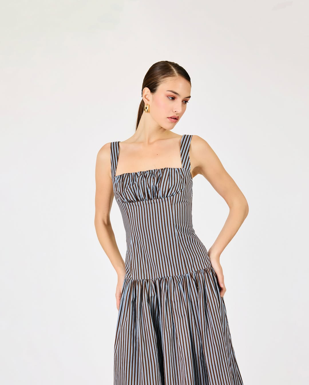 Close-up shot of the upper body showing details of the smocking on the bodice and the square neckline of the same striped maxi dress.