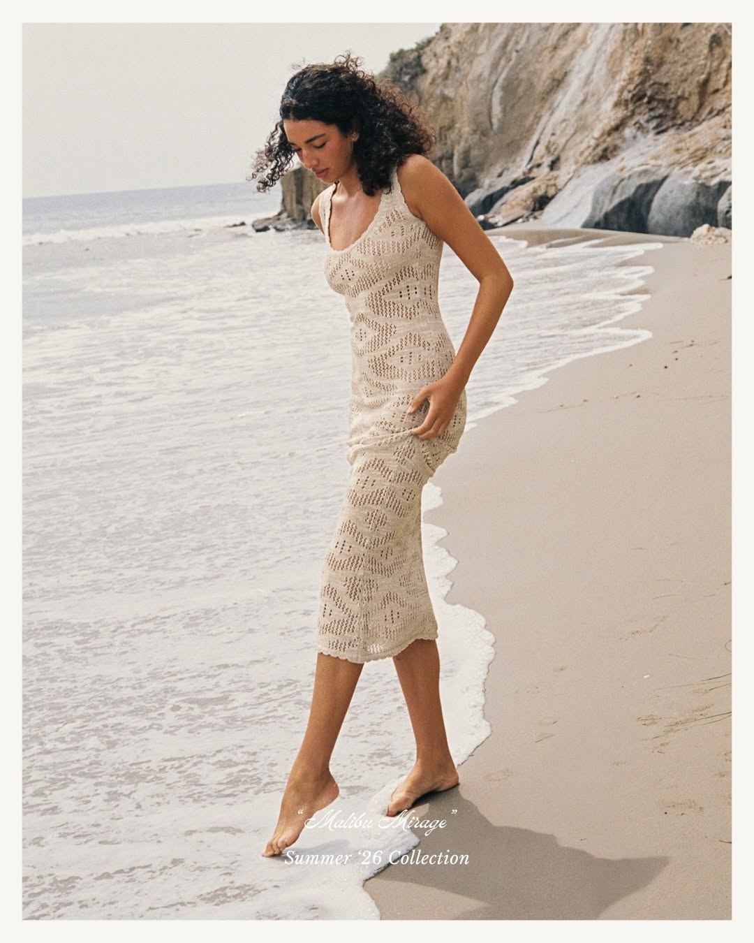 Full-body profile shot of the model walking near the water's edge.