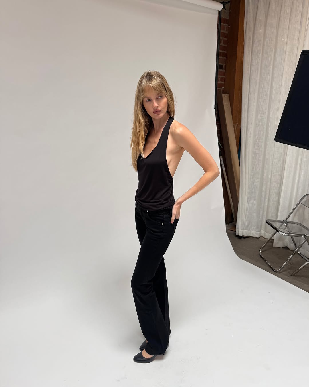 Front/side view of the black bodysuit styled with black flared trousers.