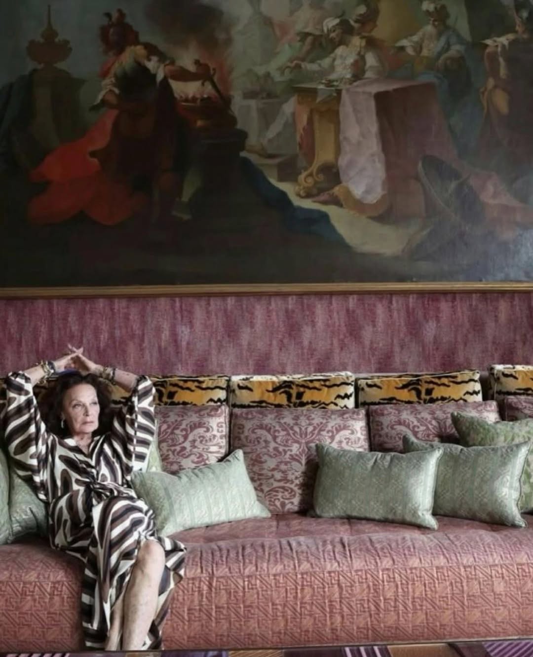 Mood image of Bette Midler relaxing on a pink velvet sofa surrounded by mixed patterns.