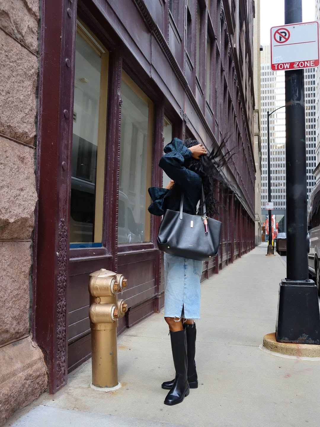Side profile of the model adjusting hair, highlighting the silhouette of the top and boots.