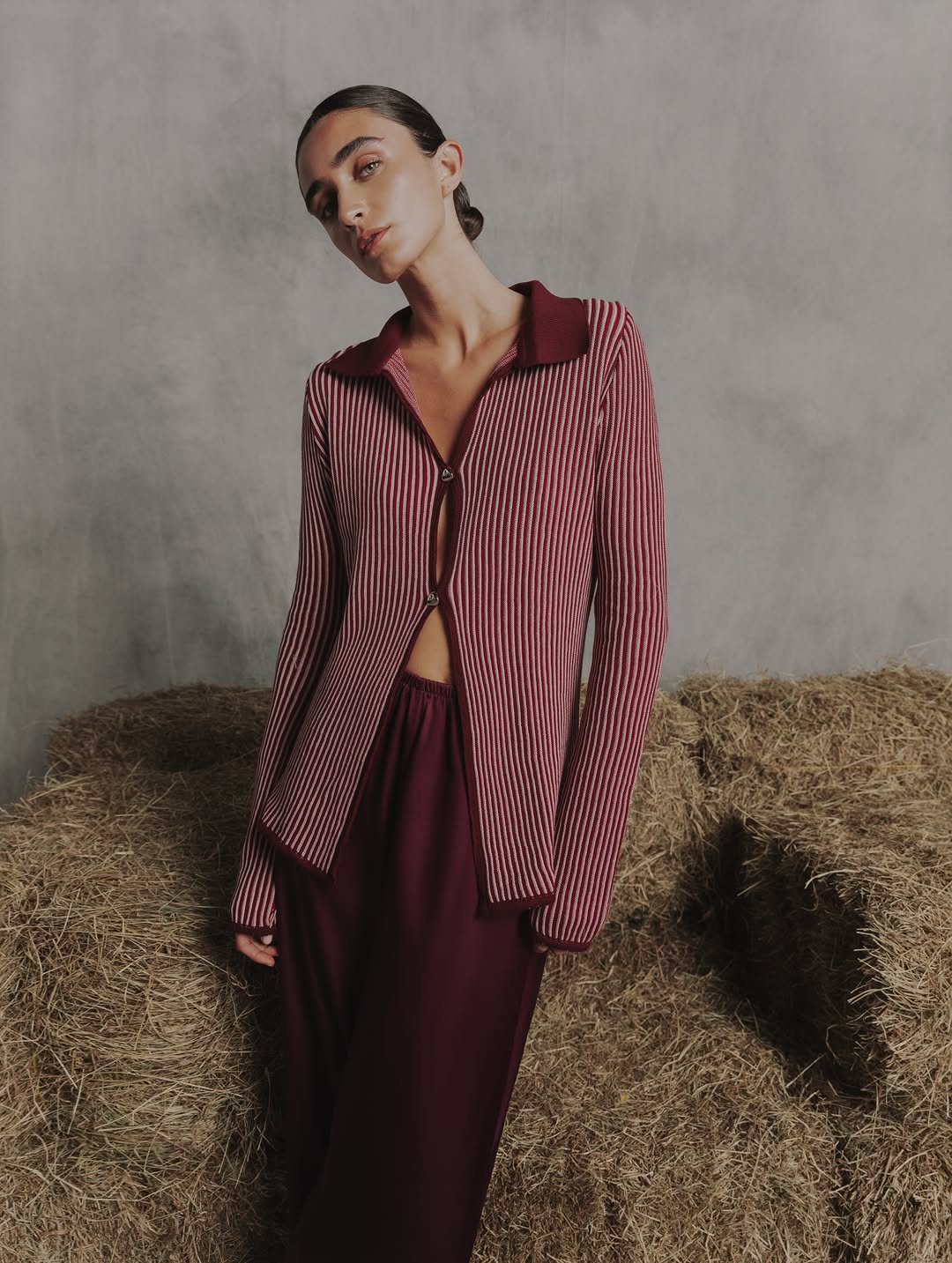 Standing pose displaying the full fit of the striped button-down shirt and flowing maroon trousers.
