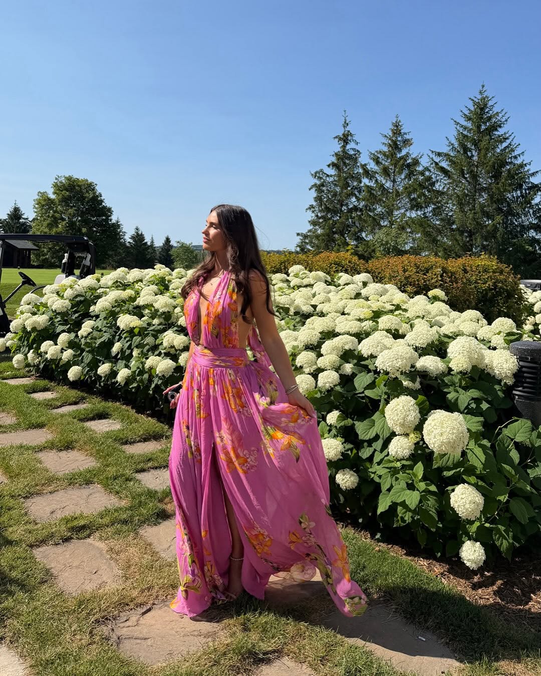Side profile view of the model in the pink floral maxi dress, showing an open back design.