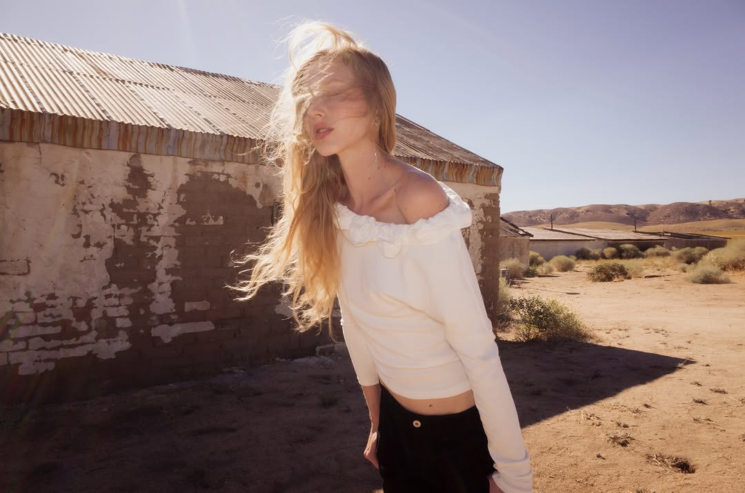 Close-up of the model in the same white ruffled off-the-shoulder top and black bottoms.