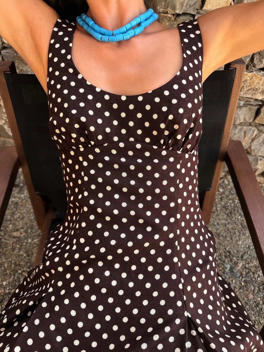 Close-up view of the bodice of the brown polka dot dress featuring wide straps and a scoop neckline.