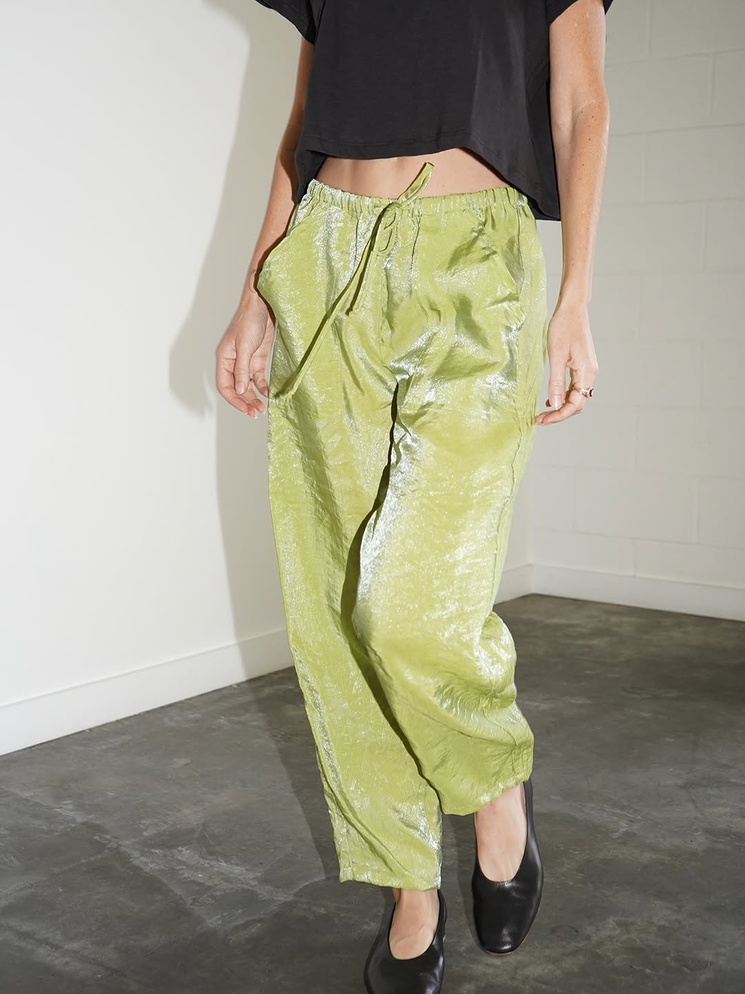 Close-up of lime green metallic-finish satin pants.