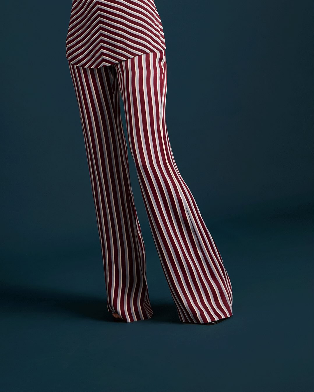 Detail shot of the lower body emphasizing the straight-leg silhouette and hemline of the striped trousers.