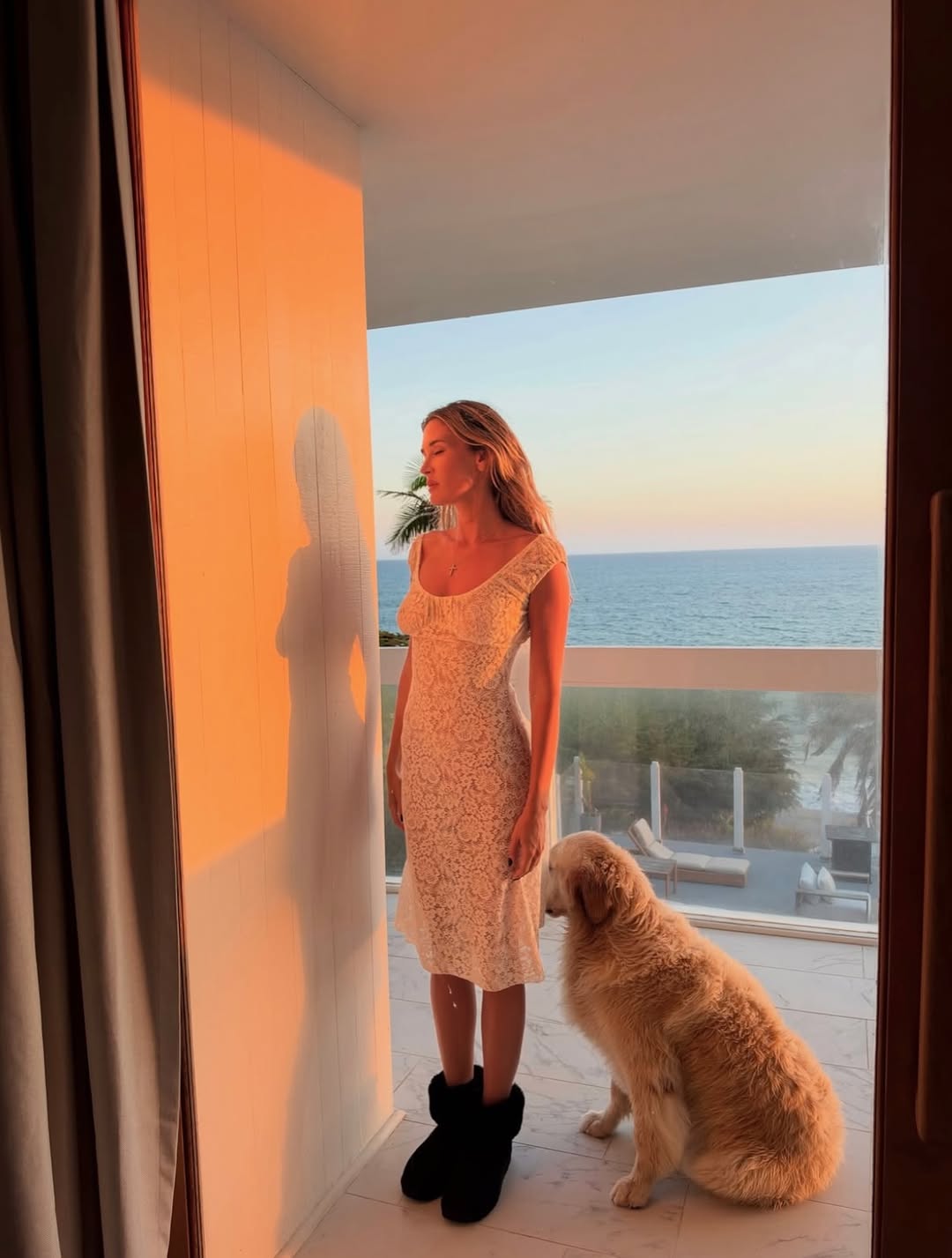 Full-body shot of model standing on a balcony wearing the cream lace dress.