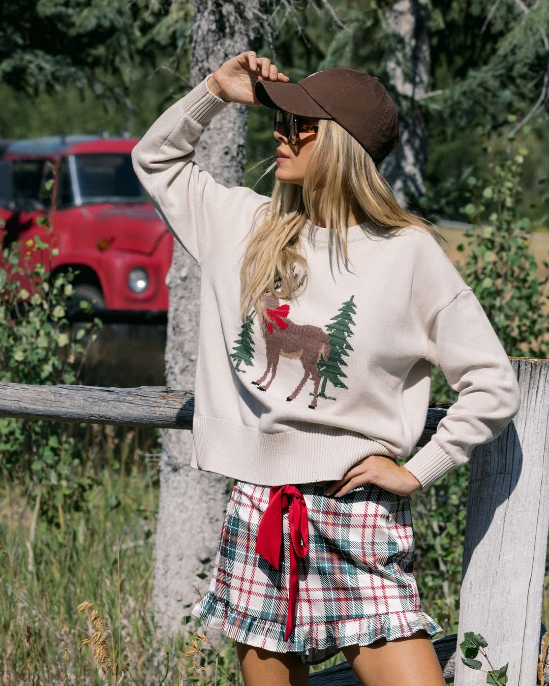 Close-up view focusing on the details of the knit sweater's deer motif and the texture of the plaid skirt.