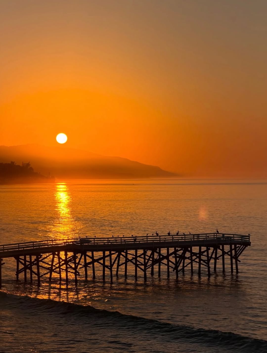 Scenic sunset over water with a pier silhouette; no fashion items visible.
