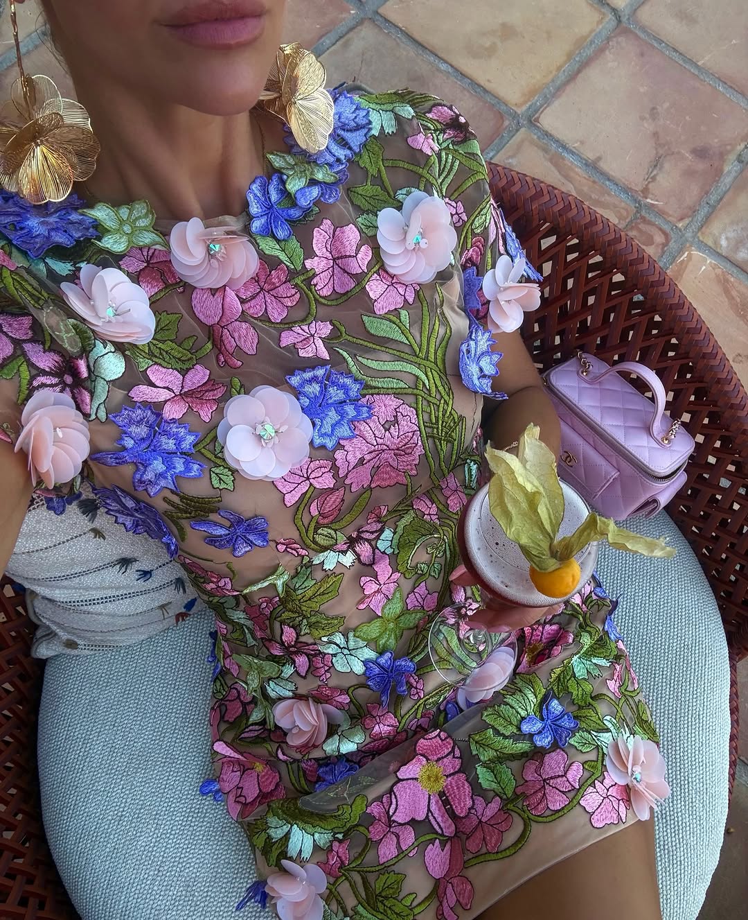 Close-up detail of the upper body showing the intricate blue, pink, and green flower embroidery on the sheer fabric.