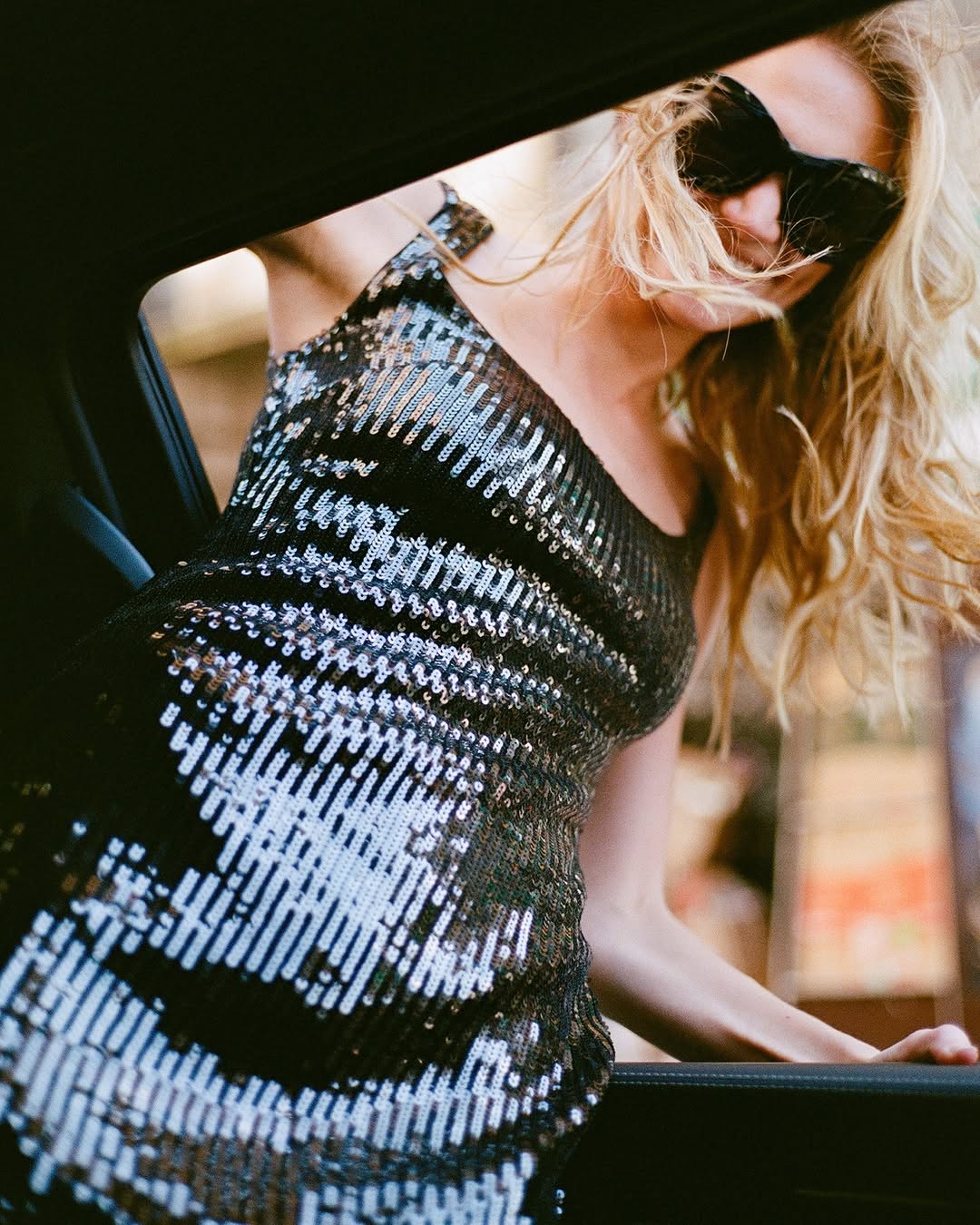 Close-up side view of the same model in the black and silver sequined midi dress.