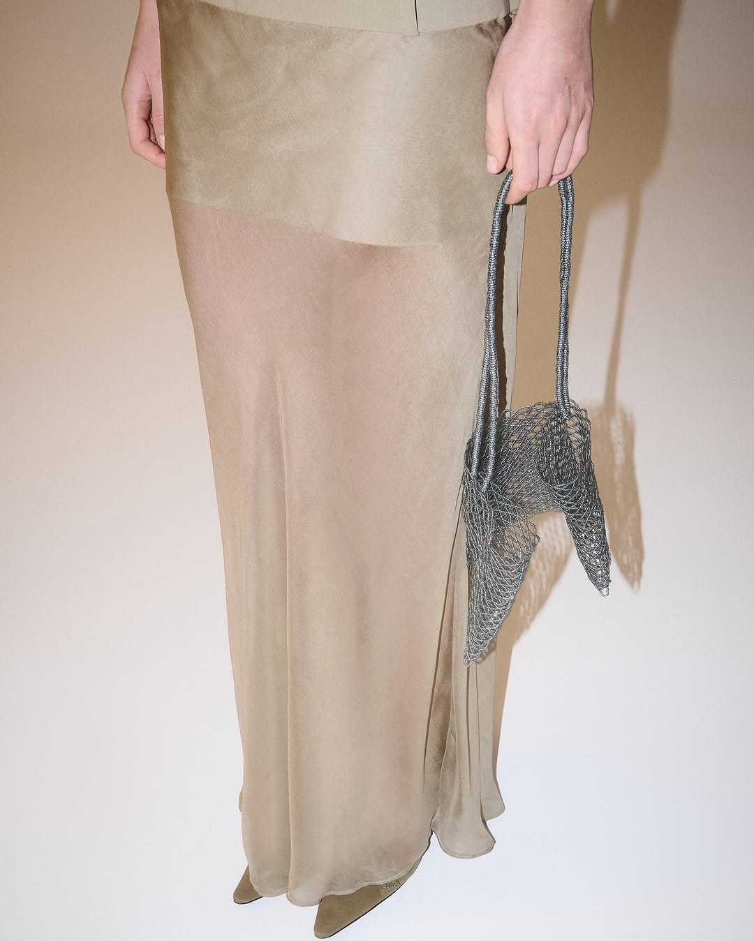 Detail view of the lower half highlighting the sheer fabric of the long skirt and the opaque underlayer.