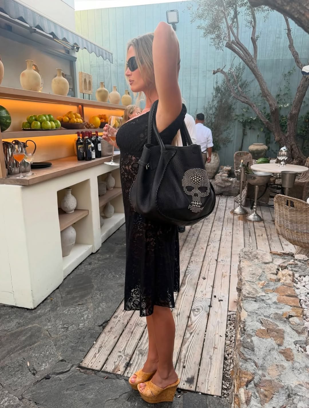 Model wearing a black version of the lace midi dress, holding the black skull tote bag.