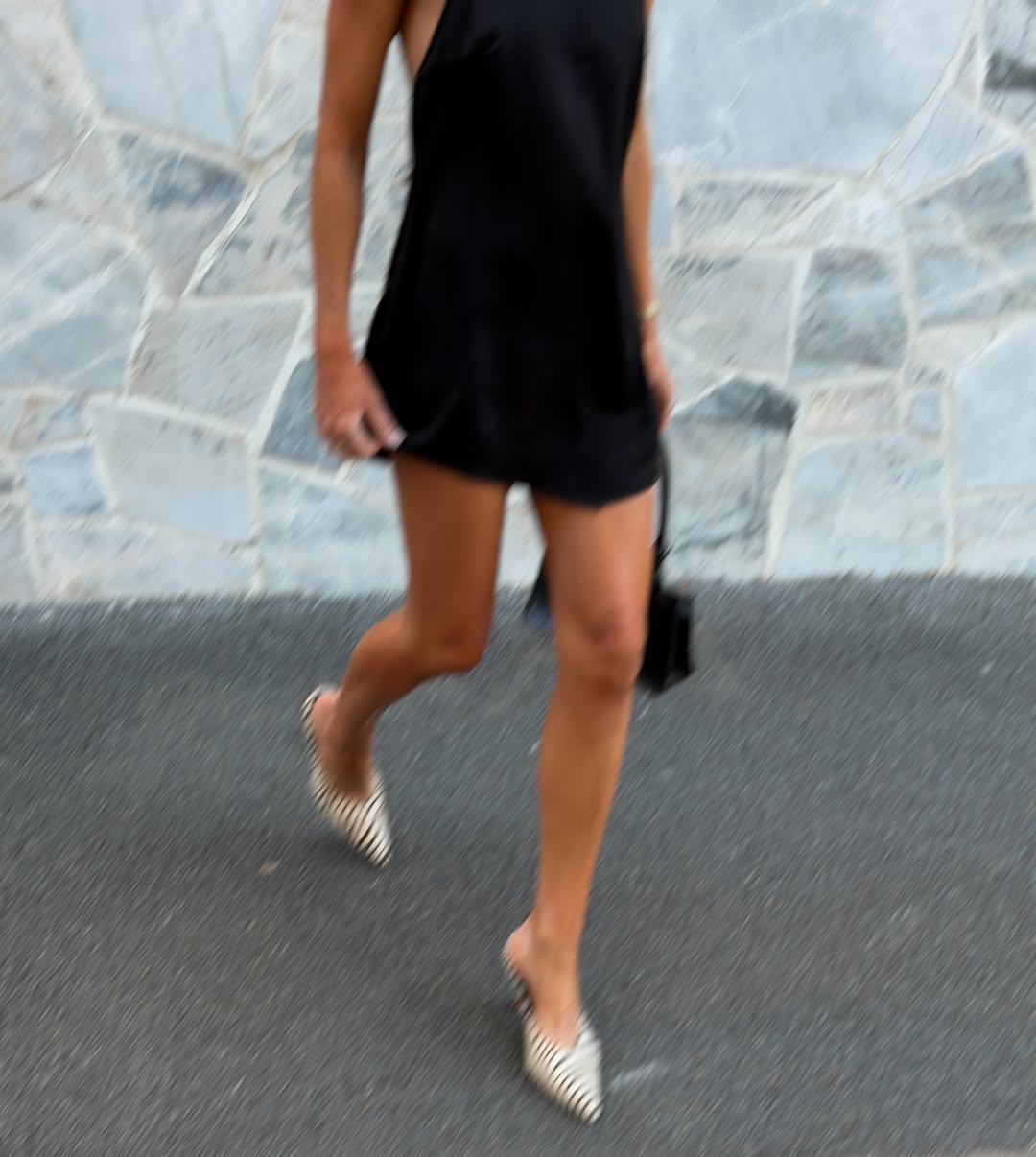 Action shot capturing movement in the same black dress and zebra-print heels.