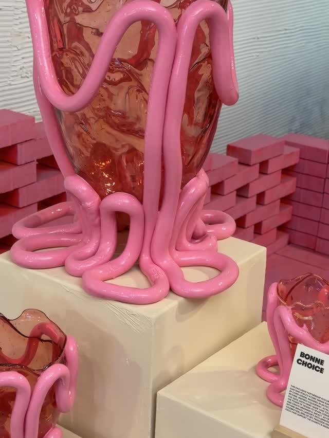 Artistic display featuring glass vases decorated with thick pink squiggly lines.