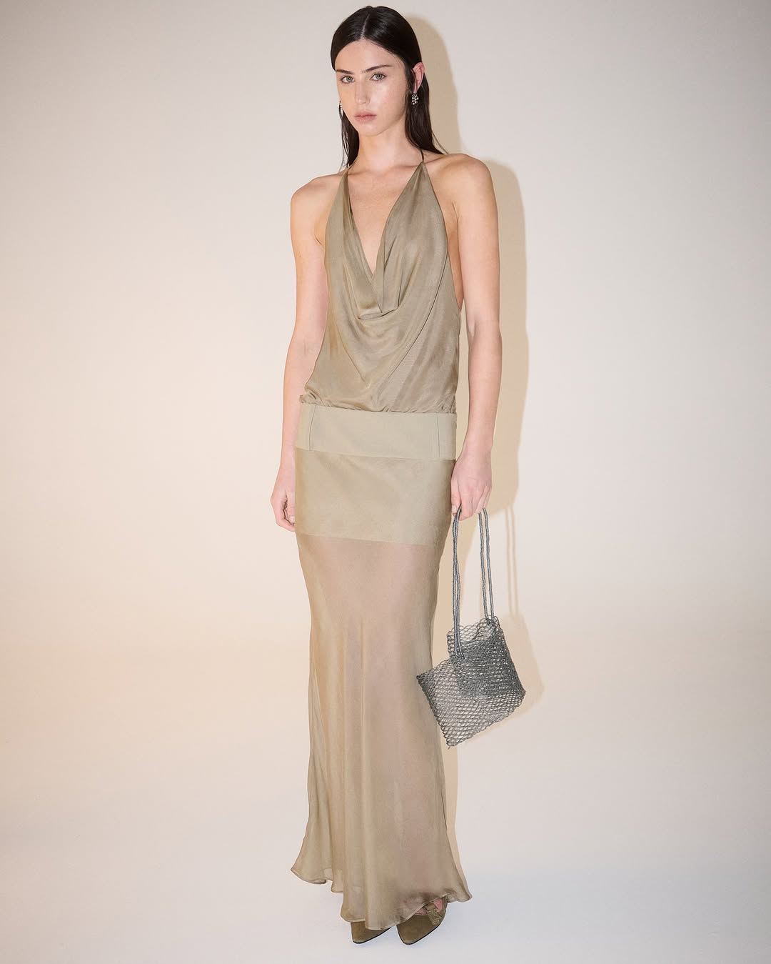 Full-body shot of the model wearing the complete taupe two-piece ensemble with a wide waistband and sheer skirt overlay.